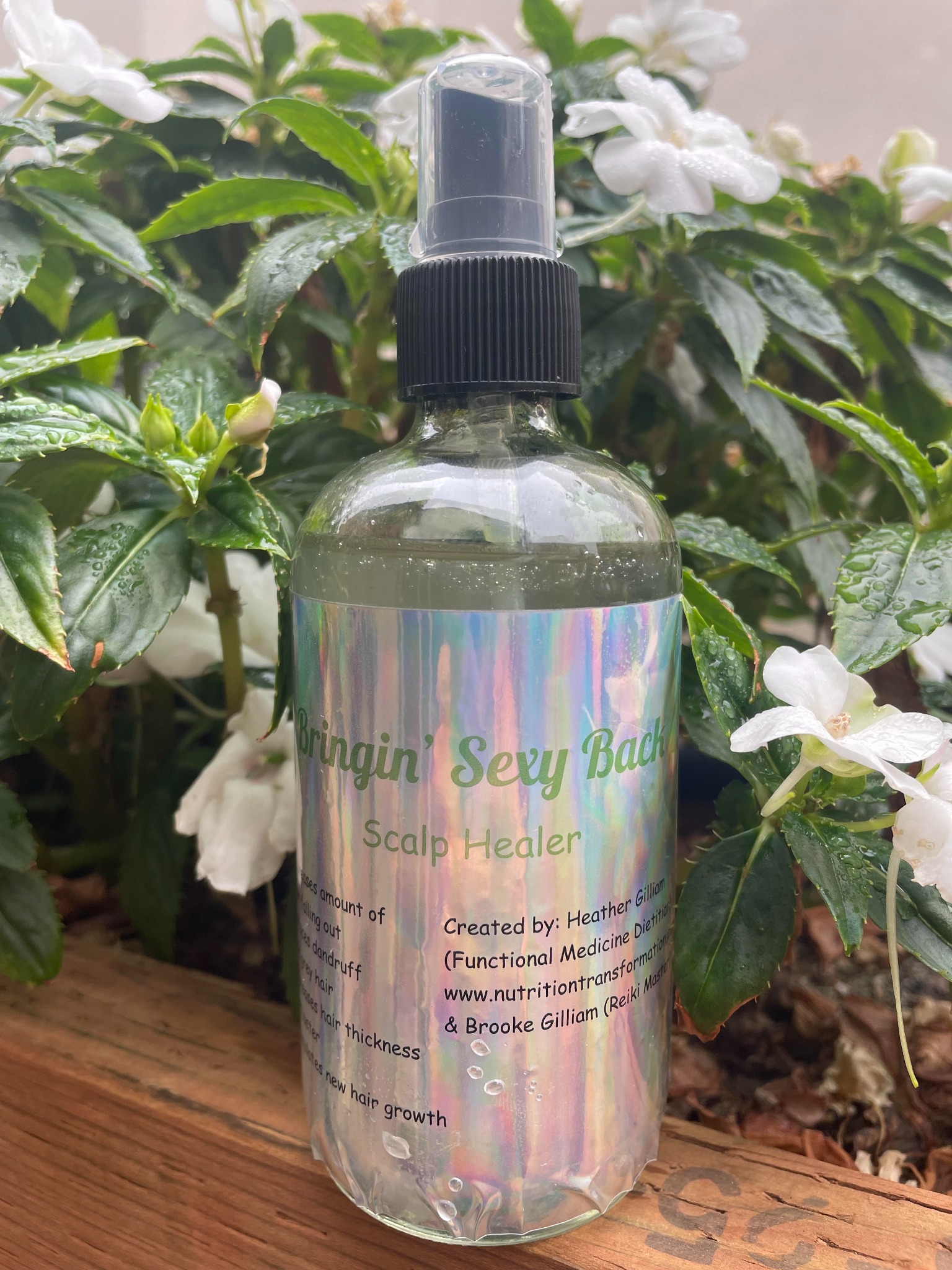 Bottle of Bringin’ Sexy Back Scalp Healer spray beside flowering plants